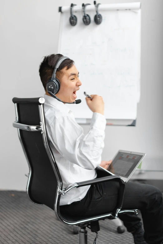 a man in headphones sitting on a chair and using a laptop computer