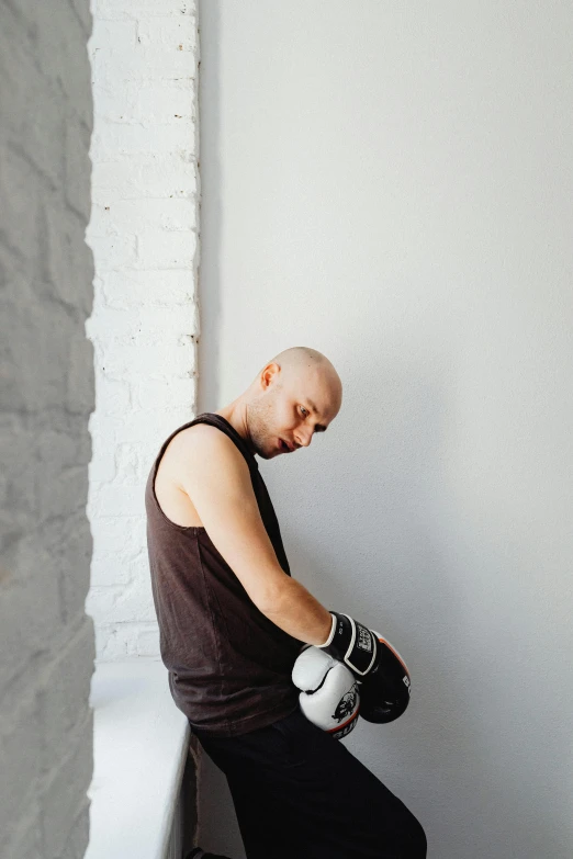 a man sitting down in a corner with boxing gloves on