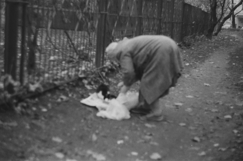 a man walking past a fence with soing in his hands