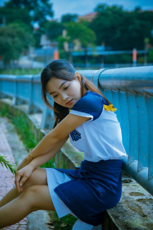 an attractive young woman sitting on the bench holding some grass