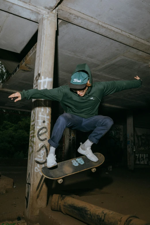 a boy in a green sweatshirt skate boarding up some wooden poles