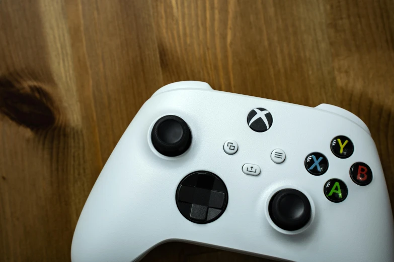 a white game controller sitting on top of a wooden table