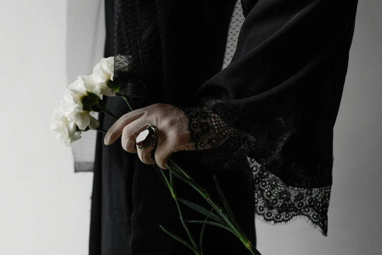 a hand holding a flower stem near other flowers