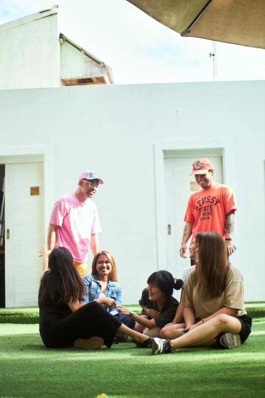 a group of people sitting outside on the grass