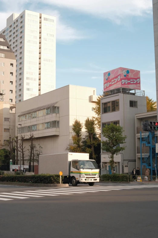 a small white van is going down a street in front of some tall buildings