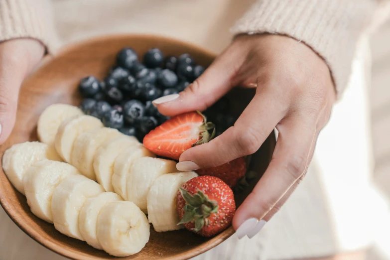 a person with a manicure that is holding a plate of fruit