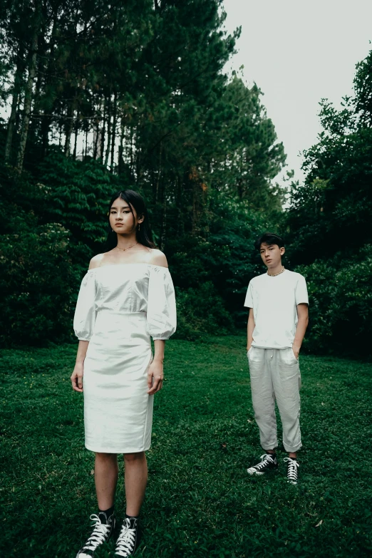 two people in white standing outside by some trees