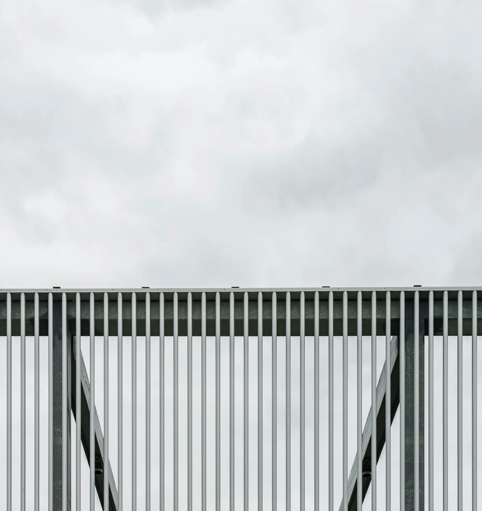 a gray metal gate on a fence next to a bench