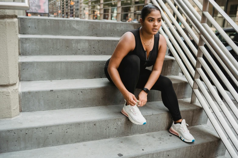 a beautiful young lady in black sports gear sitting on stairs