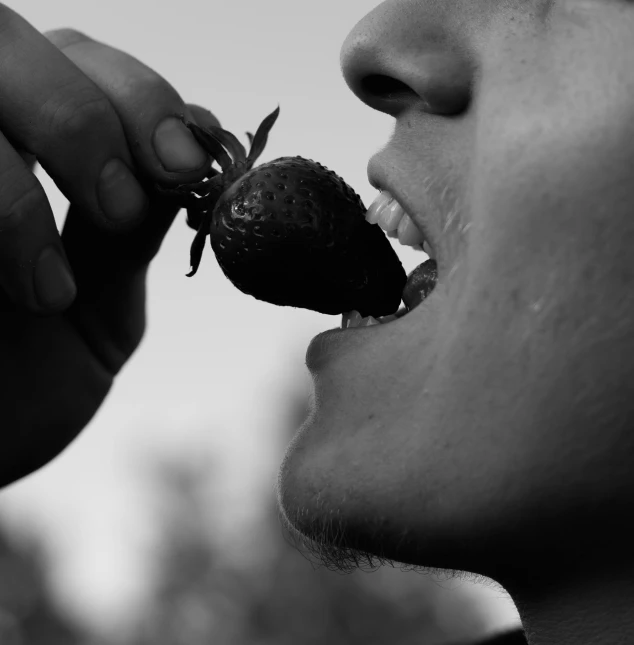 man eating a strawberries, black and white pograph