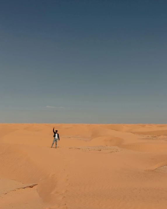 there is a man standing on a sand dune