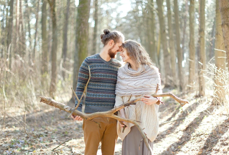 the couple walks together through a forest with leaves