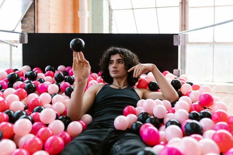 a man is sitting on a bed with many small balls