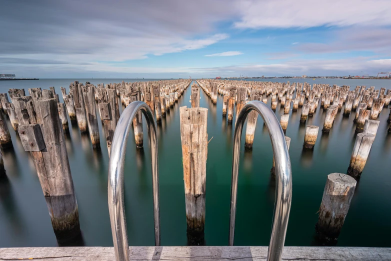 multiple old metal poles sticking out from the ocean