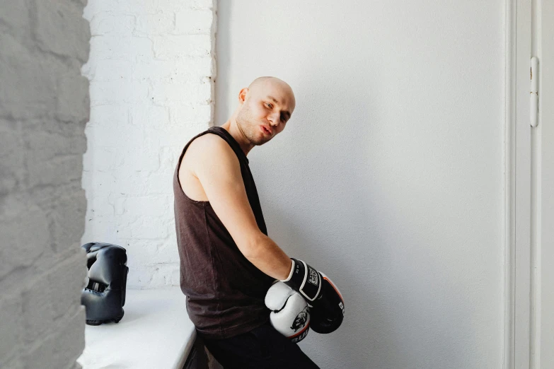 a man wearing boxing gloves next to a white wall