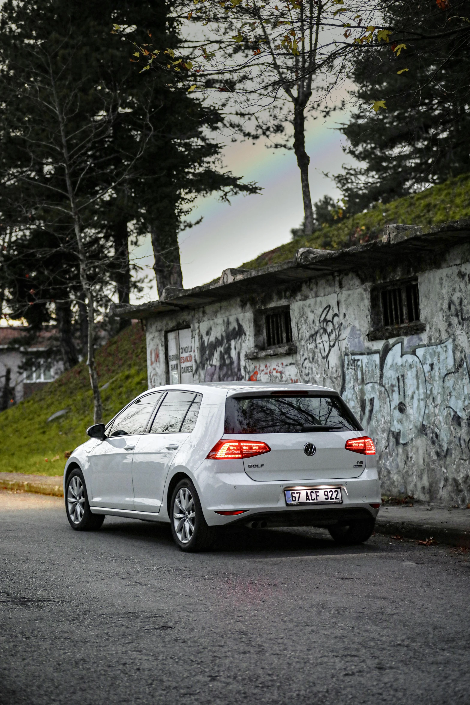 the rear end of a car parked near graffiti covered wall