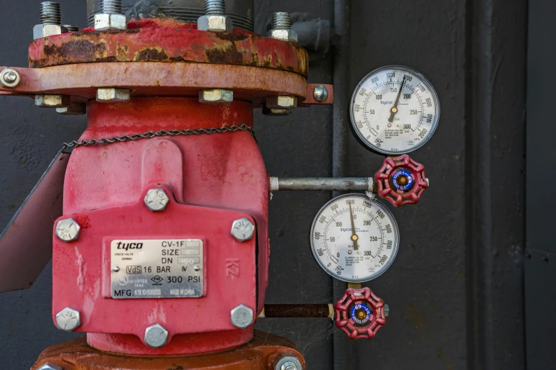 a red fire hydrant with three gauges next to it