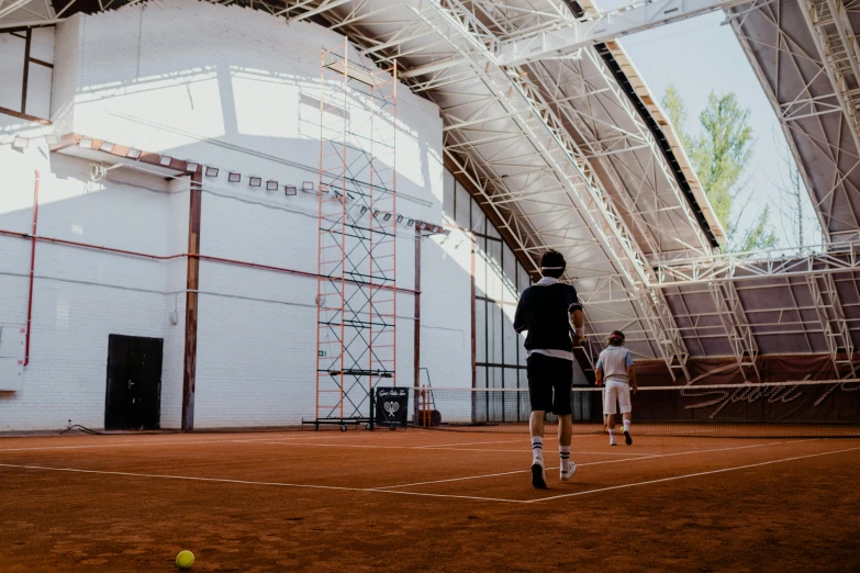 two people are playing tennis outside a big structure