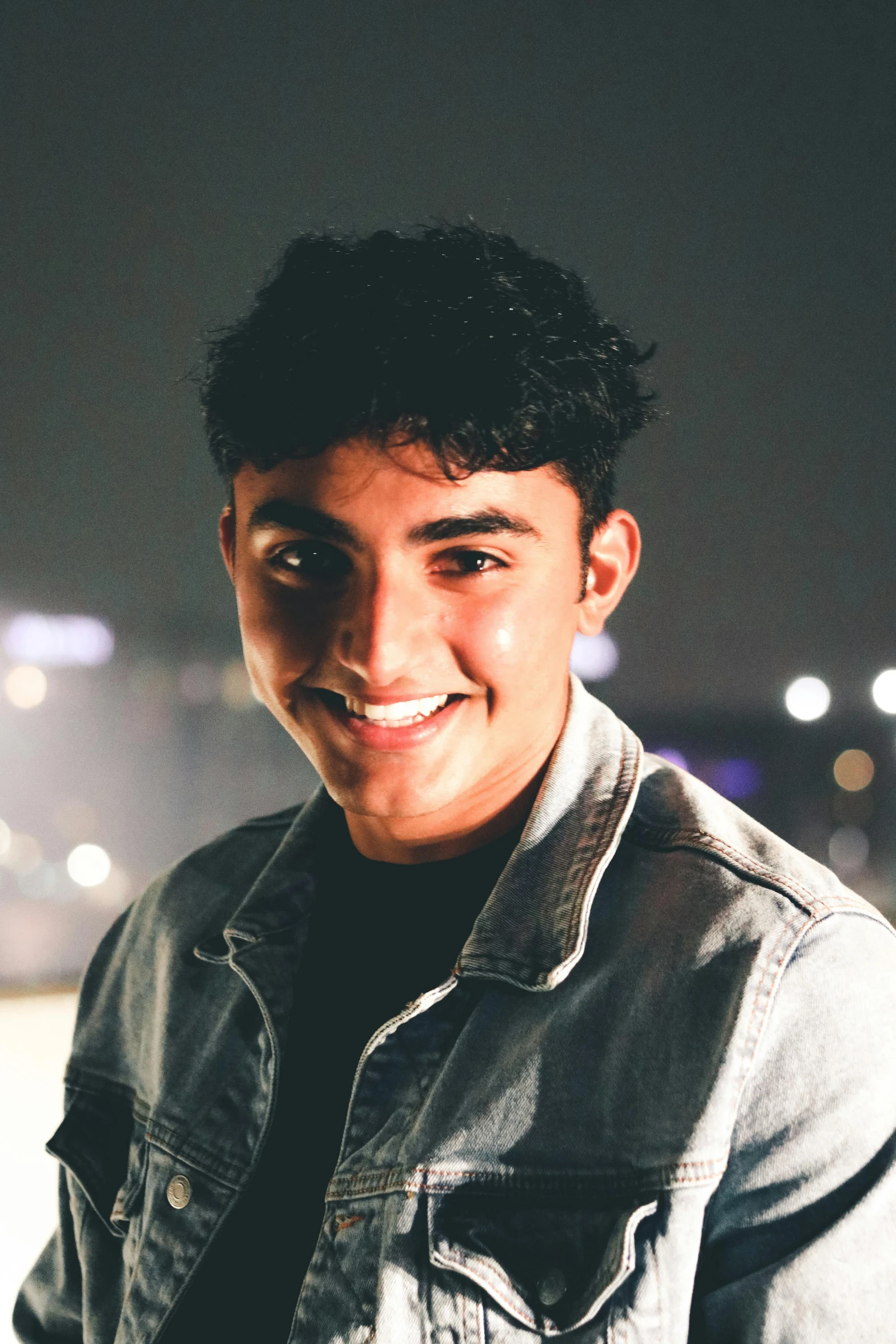 a man in jean jacket smiling for the camera