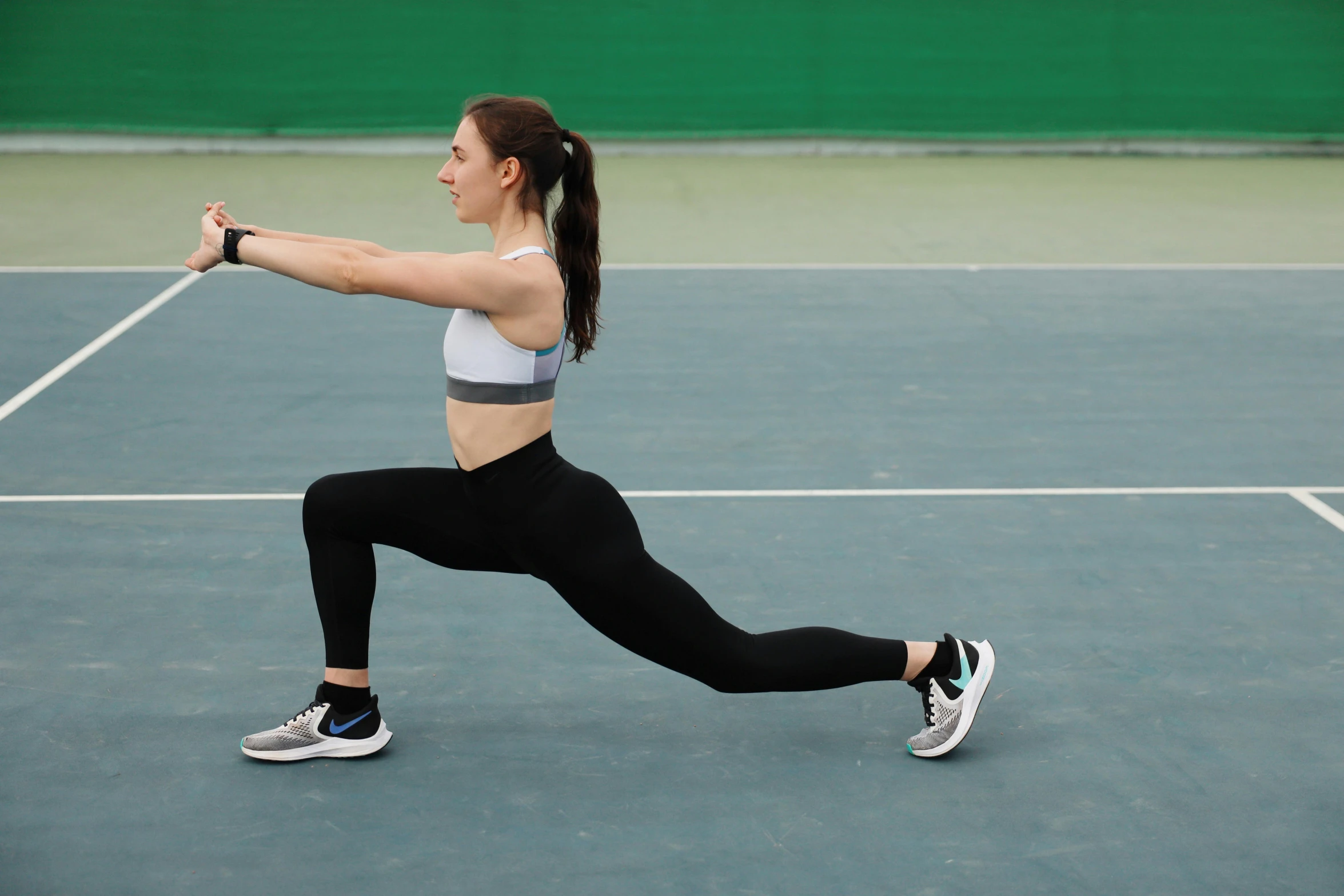 the girl in a sports  is doing some exercises on the court