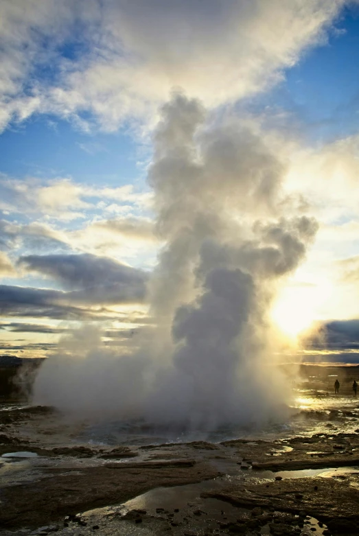 steam rises from the ground as people walk next to it