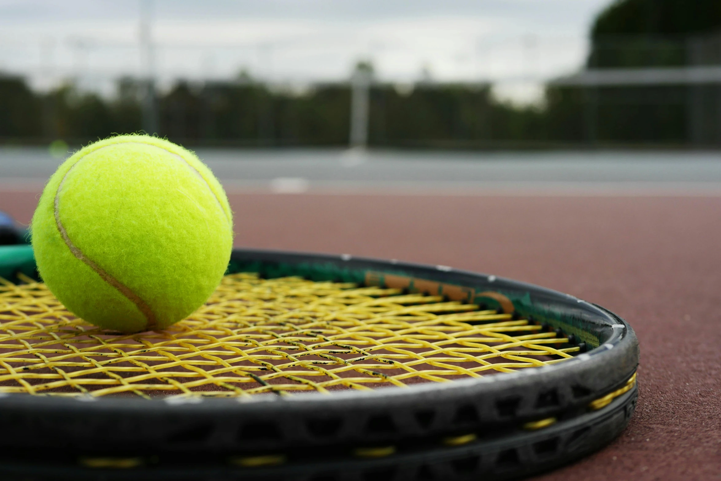 a tennis racket that has a tennis ball stuck in it