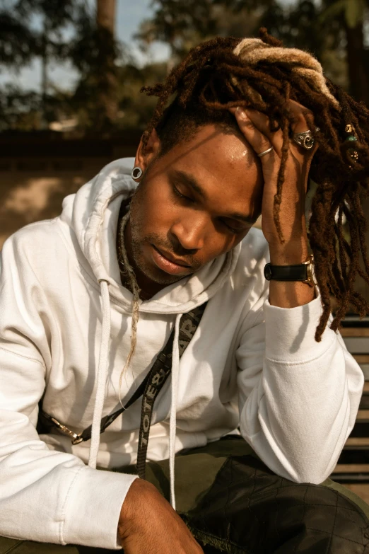 a person with dread locks sits on a park bench