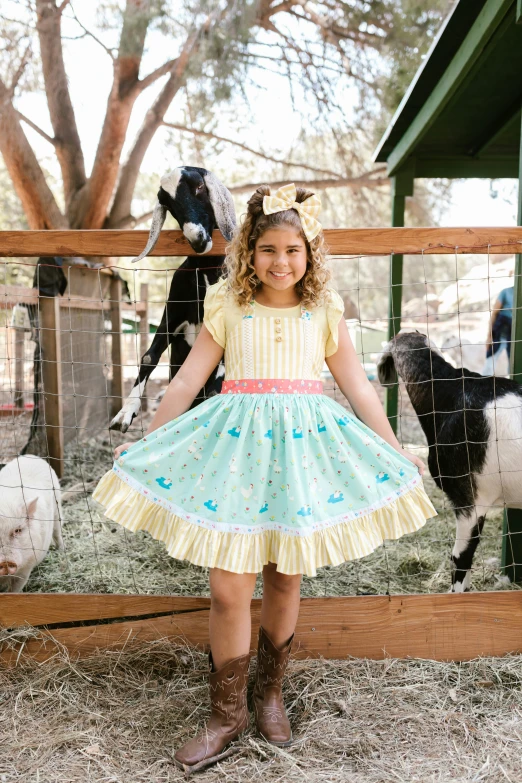 the girl is wearing a cow dress and is standing in her pen with animals