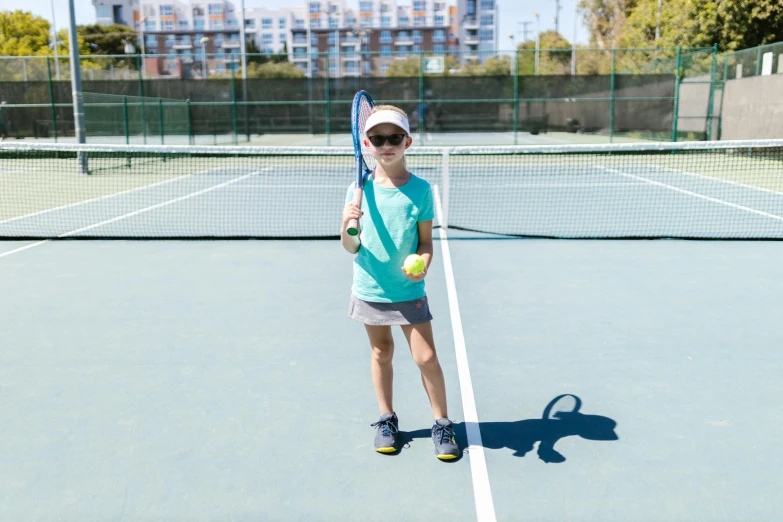 a  standing on a tennis court holding a racket and ball