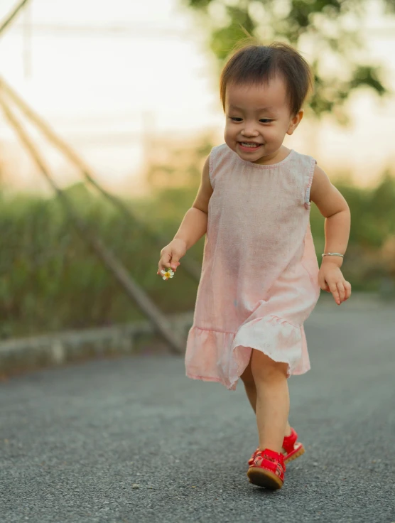 an adorable baby girl in pink dress running on street