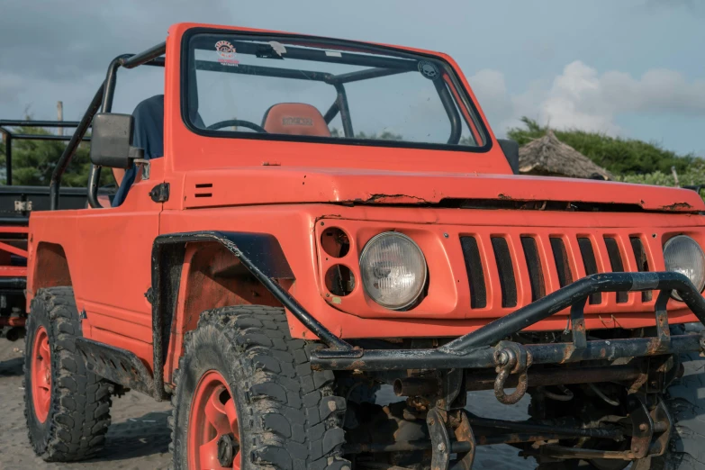 an orange jeep is parked in the sand