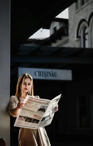 the girl is holding a newspaper reading it