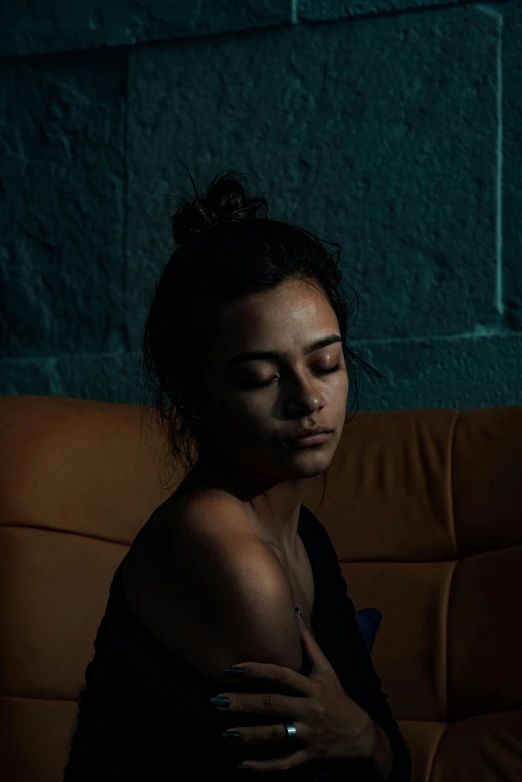 a woman sitting on a brown couch in a dark room