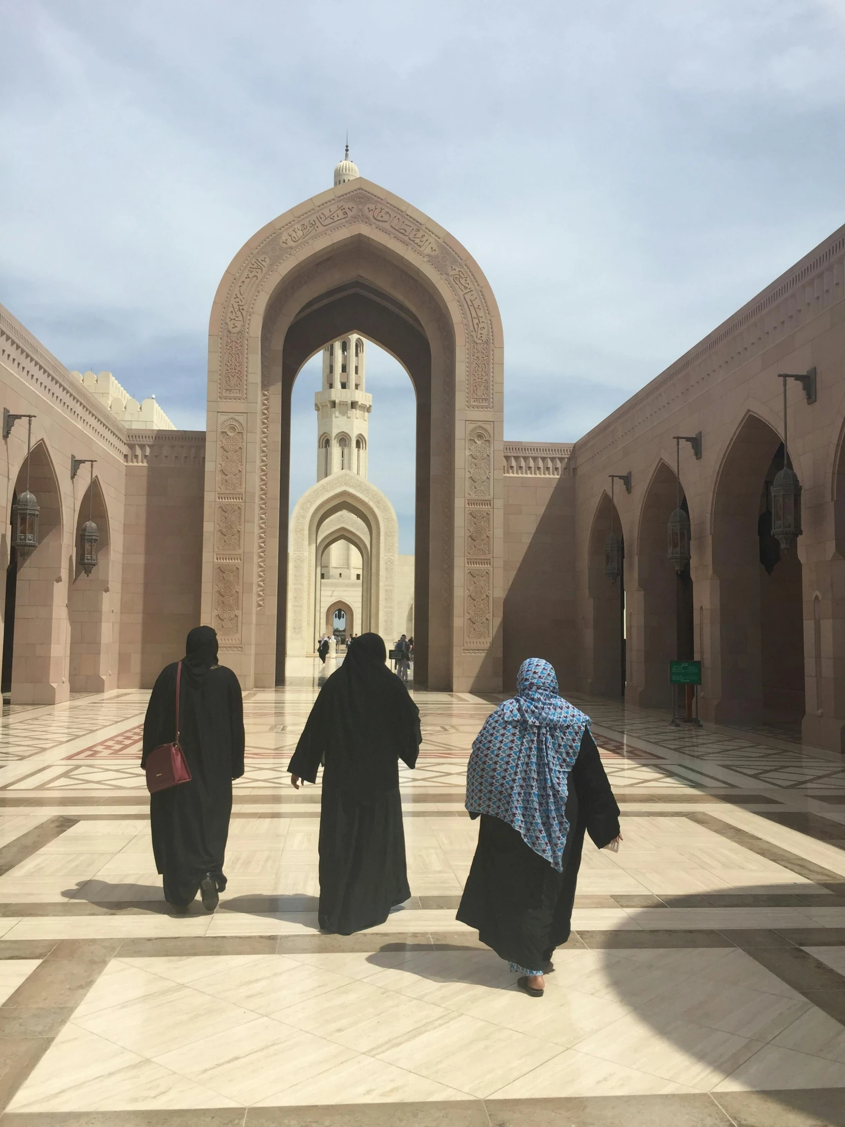 women in traditional dresses walking through a courtyard