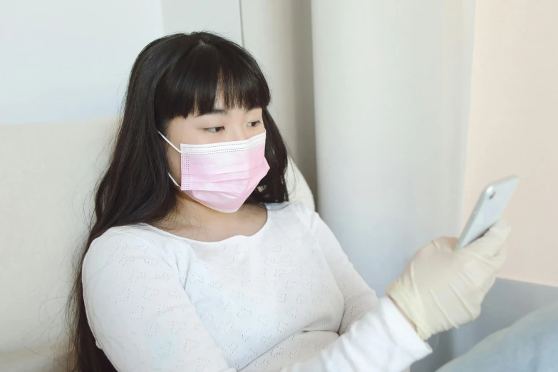 a woman in white top and pink surgical mask