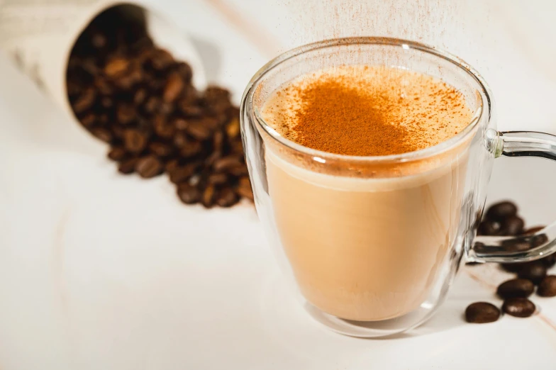 a glass filled with liquid next to coffee beans