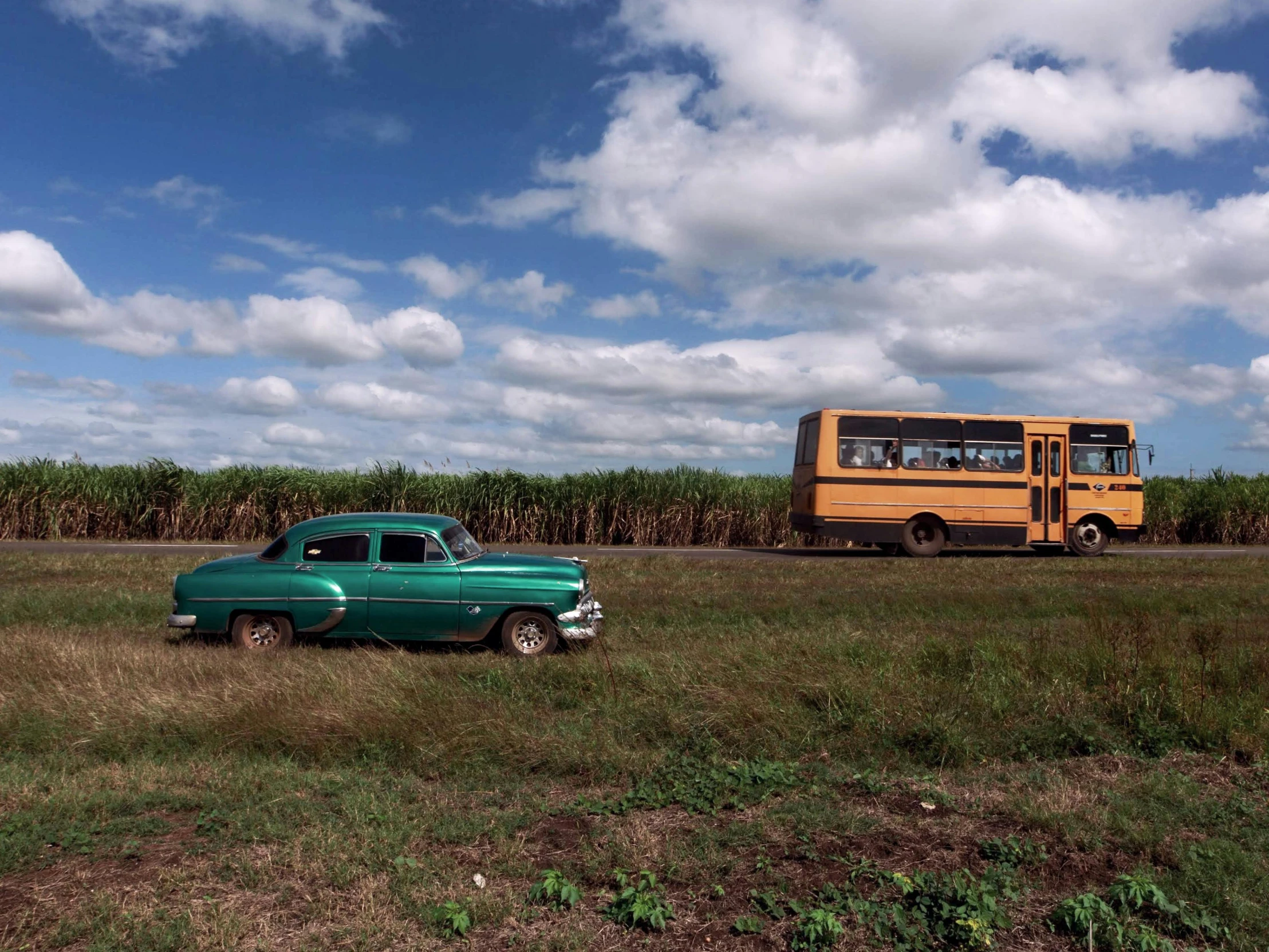 two large buses parked near a grass covered field