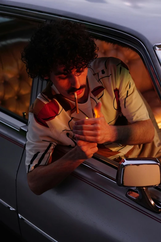 man leaning out of the car window holding an object