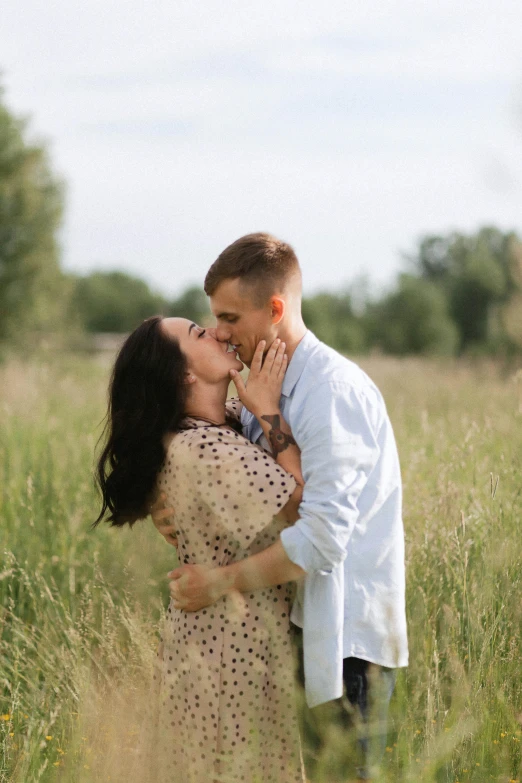 a couple kissing and smiling while standing in tall grass