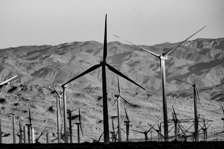 windmills are near some mountains in the desert