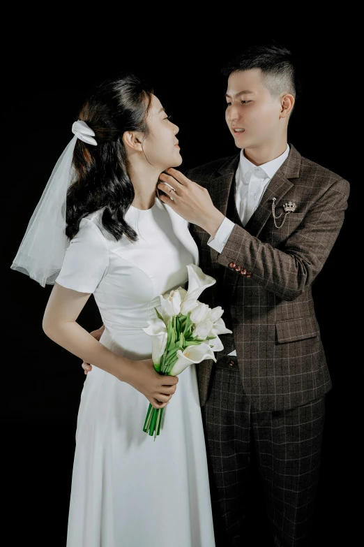 an asian couple putting a wedding flower on their forehead