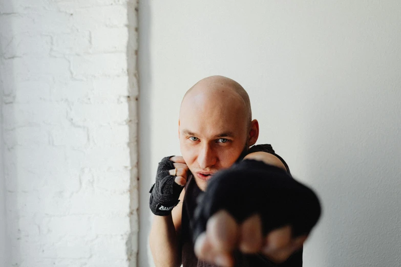 man with bald head pointing a gun at the camera