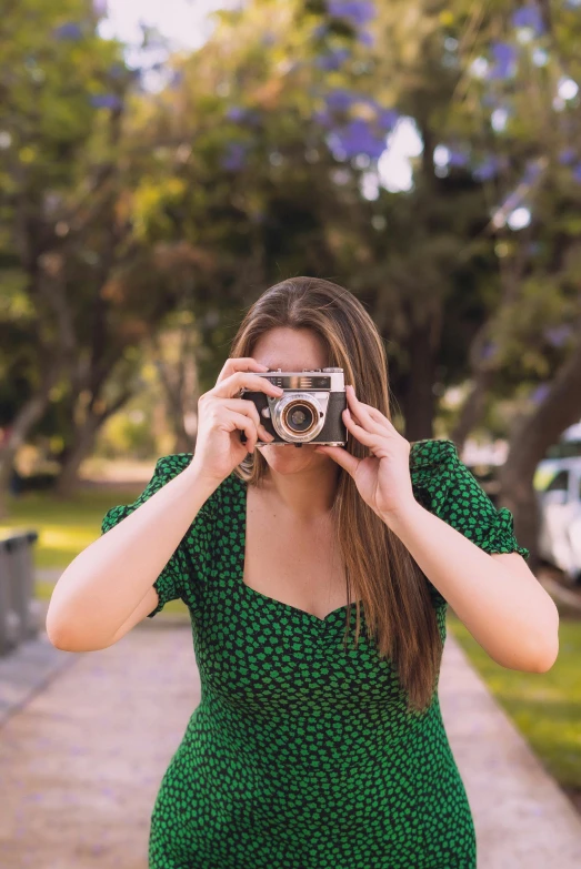 the young woman is taking pictures with her old camera