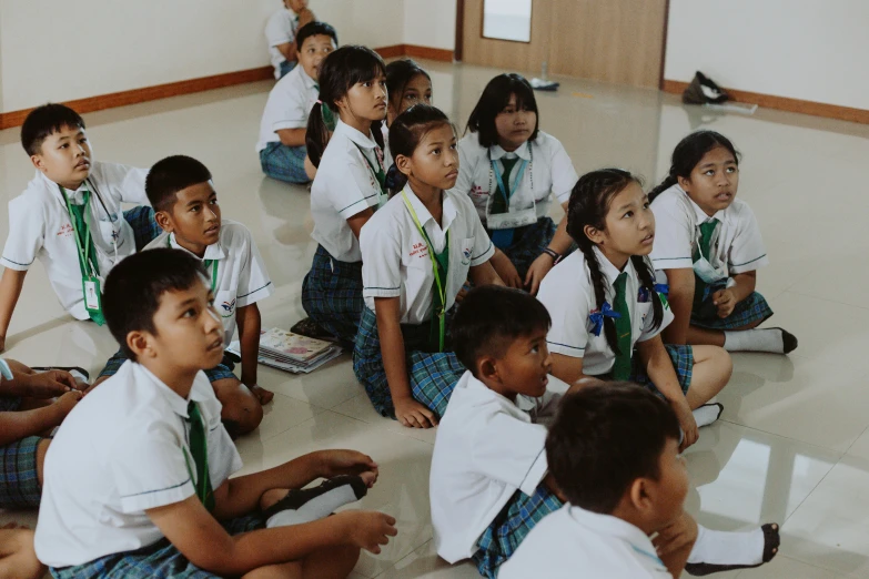 many young students are sitting on the floor