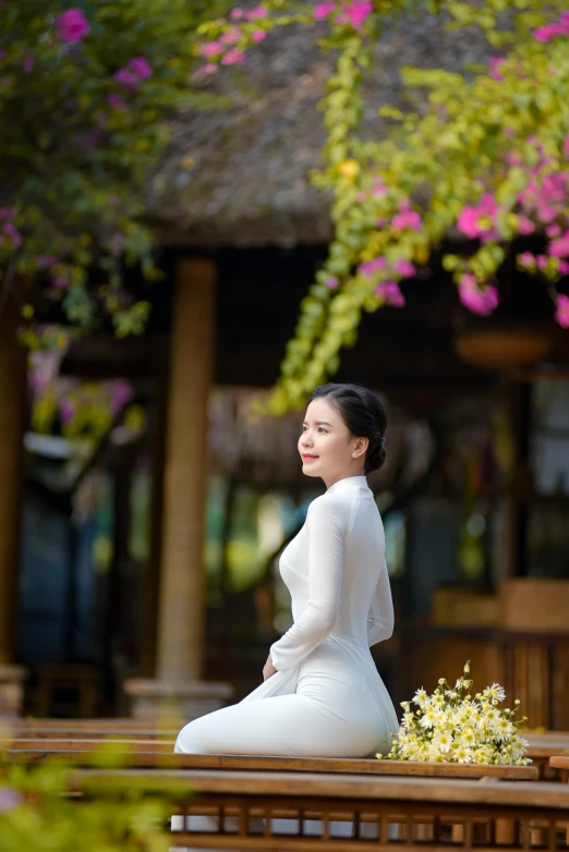 a woman wearing a dress is sitting on a table and looking up