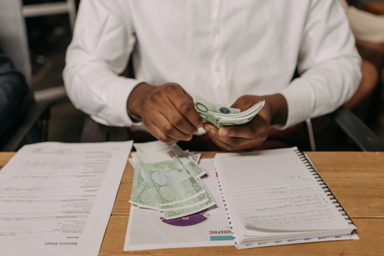 a person sitting at a table counting money