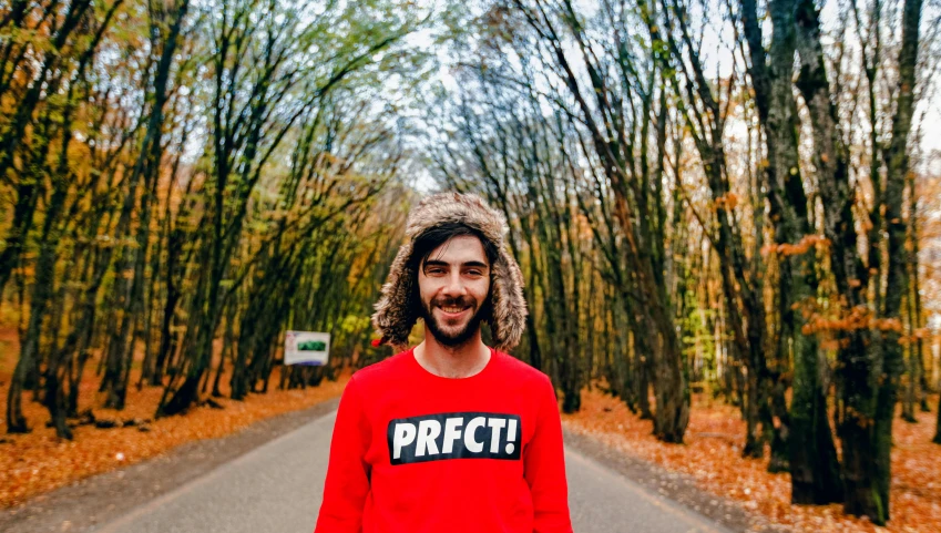 a man with a shirt saying perfect in the front is standing on the street