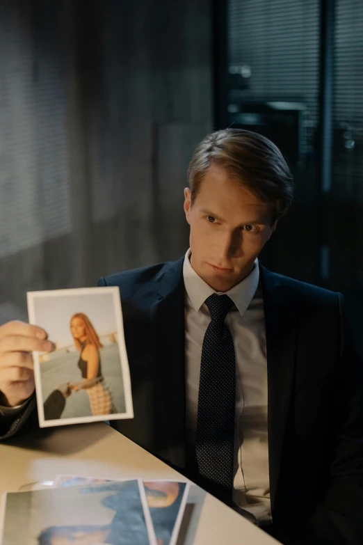 a man sitting at a table holding pictures of himself