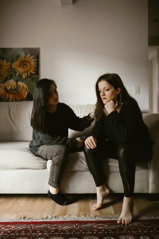 two women are on a couch talking and laughing