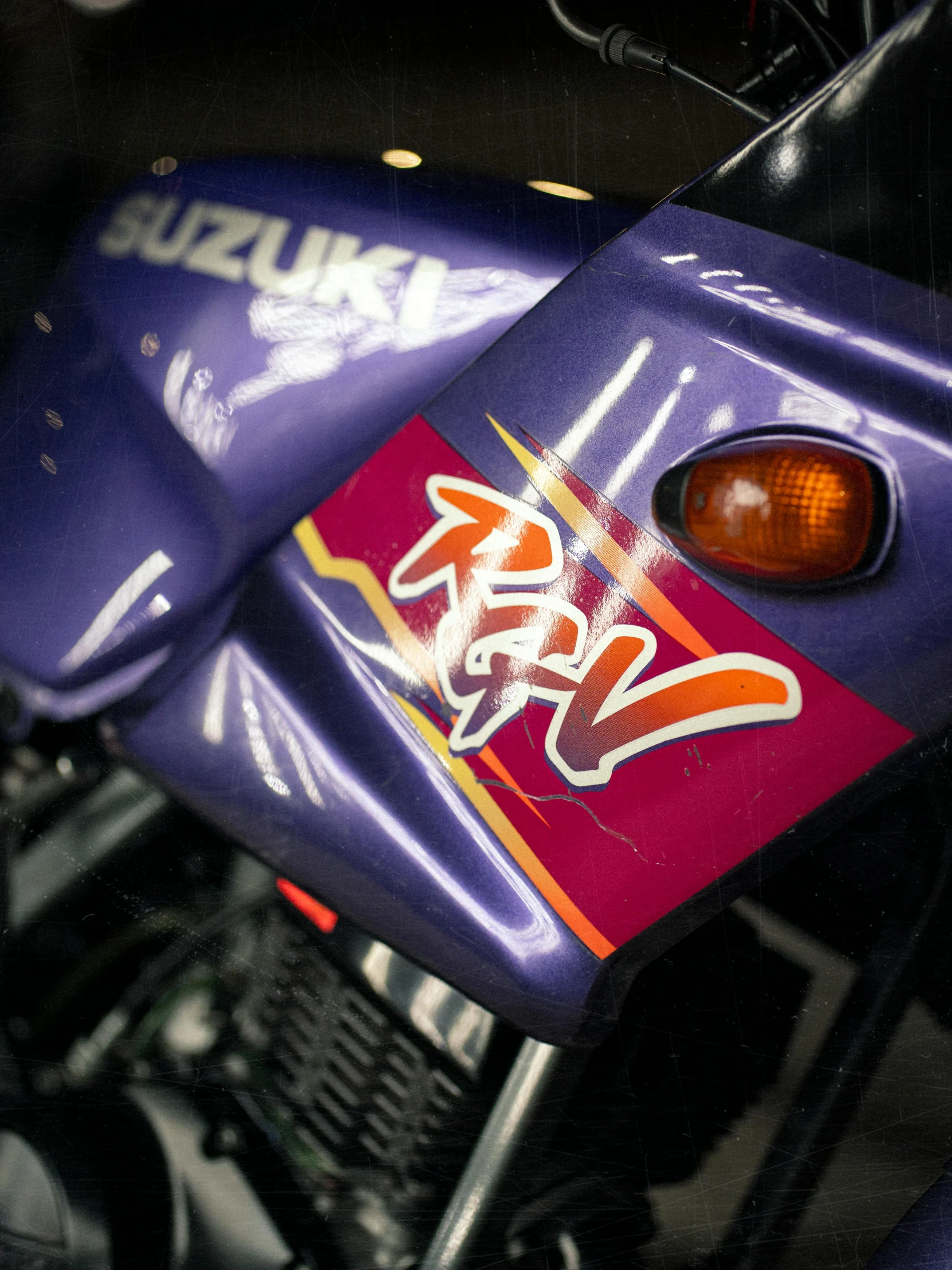 a shiny, purple motorcycle has a graffiti covered taillight